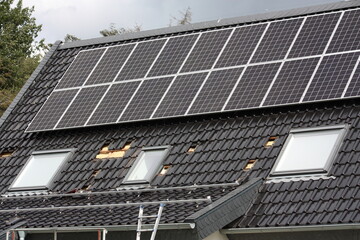 Montage einer Photovoltaikanlage auf dem Dach, mit Baugerüst und Leiter bei Sonnenschein in...