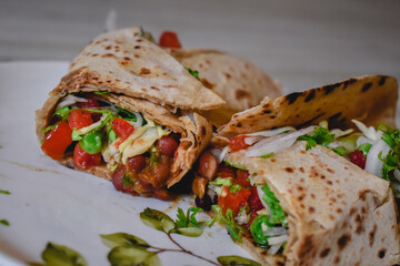 Tortilla wrap sandwiches with mexican beans and vegetables in dish