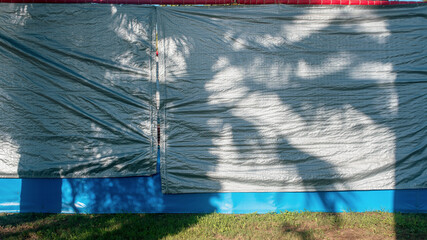 tarpaulin canvas material covered large building wall on construction site - obrazy, fototapety, plakaty