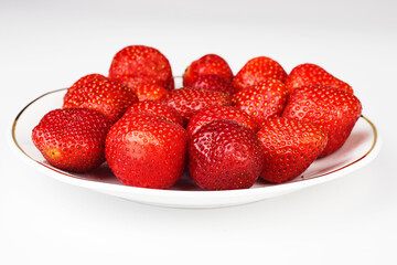 Large and ripe strawberries on a white saucer.