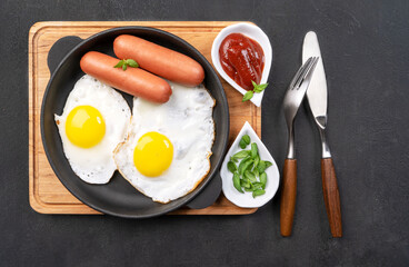 morning breakfast. Fried eggs with sausages in a frying pan.