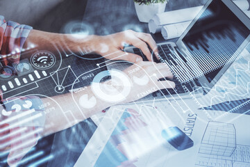 Technology theme hologram with man working on computer on background. High tech concept. Multi exposure.