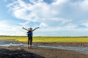 Fototapeta premium Young woman travel and explore adventure raise hands in nature. Asian people jumping relax for destination leisure landscape forest in summer day. 