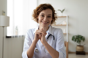 Head shot portrait smiling woman doctor wearing white uniform consulting patient online, friendly...