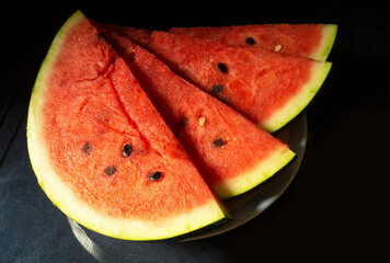 The Ripe watermelon in plate on black background.The Slices fruit with red pulp. Sweet products of the feeding