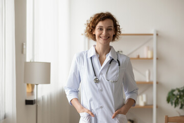 Portrait smiling beautiful young woman wearing white coat uniform with stethoscope, doctor standing...