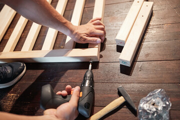Carpenter hobbyist assembling wooden boards at home / garage.