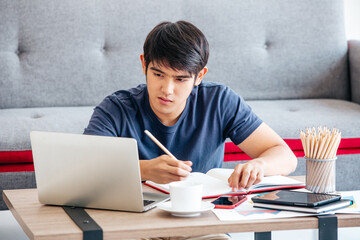 Serious man writing notebook on desk in the Living room. COPY SPACE. Trading. Working. WORK FROM HOME Concept.