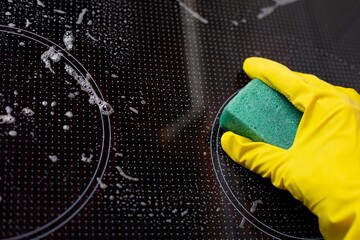 A woman in a yellow rubber glove cleans a ceramic slab