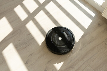 Robotic vacuum cleaner on laminate wood floor in living room