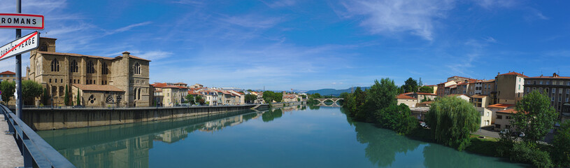 Fototapeta na wymiar Panoramic view of the Isere river on the Old Bridge connecting Romans-sur-Isere to Bourg de Peage