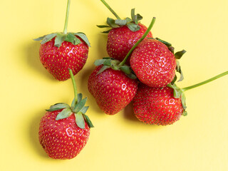 top view of juicy ripe strawberries lying on a bright yellow background. Healthy and delicious berries, vegetarian food, healthy food