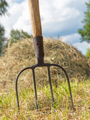 a pitchfork for agriculture is stuck in the ground against the background of a haystack.