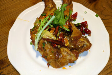 two fresh fried rabbit's legs with vegetables and peppers on the white plate