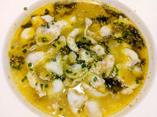Boiled Fish with Sichuan Pickles with scallion in white plate  under bright light