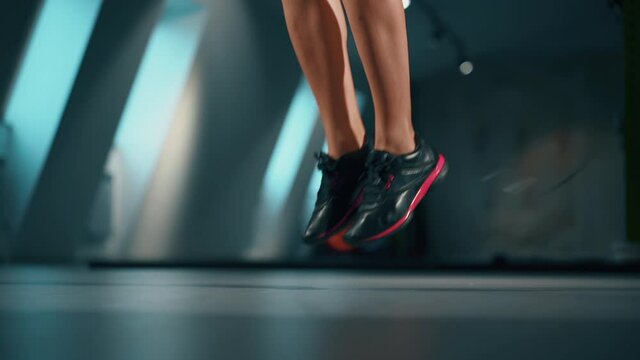 Workout with elements of cardio. A female feet in sneakers jumping with a skipping rope. Person jumps in training in the gym. Leg muscle pumping. Concept of athletic, lifestyle, physical, sportswear