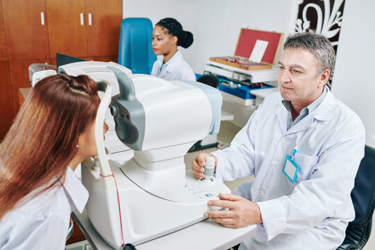 Opthalmologist checking oculus fundus of female patient via non-mydriatic camera