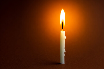 One light candle burning brightly in the black background