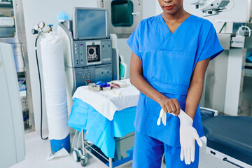 Cropped image of medical nurse putting on rubber gloves and getting ready for surgery
