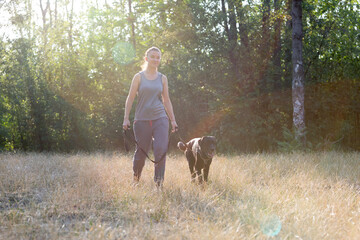 Young attractive sport girl walking with black Labrador in park. Healthy lifestyle. Walk with favorite pet in wood.