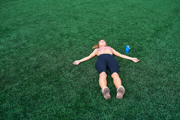 Sports girl lies on a green field