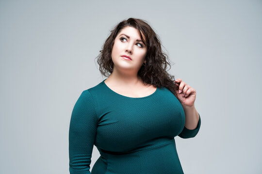 Plus size fashion model in green dress, fat woman on gray background, body positive concept