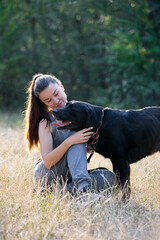 Young attractive sport girl with black Labrador in park. Healthy lifestyle. Walk with favorite pet in wood.