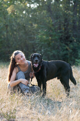 Young attractive sport girl with black Labrador in park. Healthy lifestyle. Walk with favorite pet in wood.