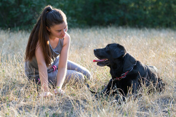 Young attractive sport girl with black Labrador in park. Healthy lifestyle. Walk with favorite pet...