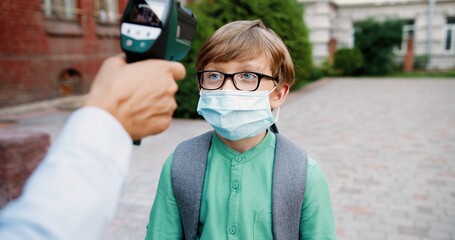 Close up portrait of mixed-races junior students going to school after lockdown. Measuring of...