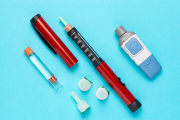 Diabetic set of lancet with spare needles, strips, box of spare strips, pen injector, spare insulin and pen needles on a blue background