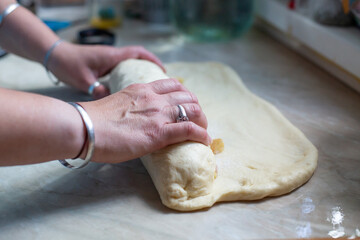 Women hands forming dough for apple pie with raisins.Pie filling with apples and raisins. Yeast dough for pie.