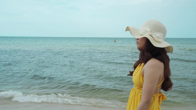 young woman in yellow dress walking on the sea beach