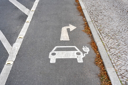 Parksymbol auf Asphalt f&uuml;r Elektroauto Ladestation mit Wegweiser nach rechts