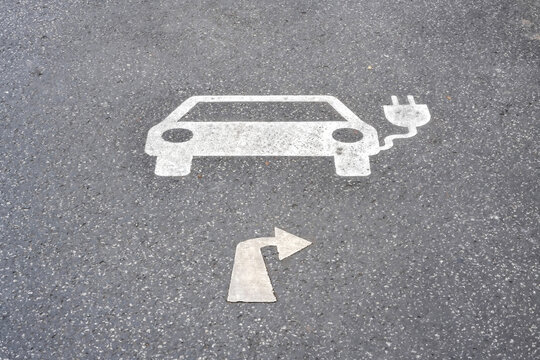 Parksymbol f&uuml;r Elektroauto Ladestation mit Wegweiser nach rechts auf Asphalt 
