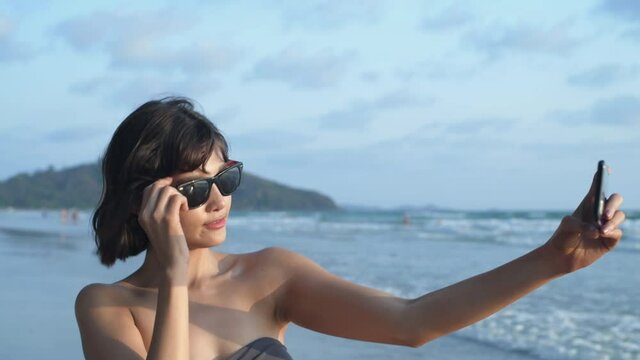 Travel concept. Asian girls happily taking photos on the beach. 4k Resolution.
