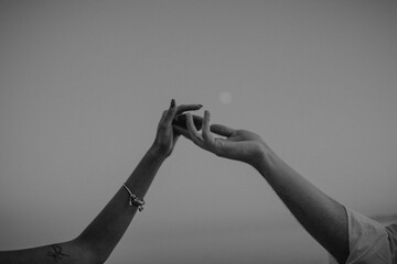 intertwined hands of a man and a woman on a gray background,