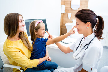 Obraz premium Friendly pediatrician having fun with her child patient at the hospital. Consultation, kid health.