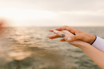 Gently holding hands against the background of the sea.