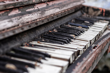 Old broken red piano with peeled paint from rain and wind, outside on an autumn day. Discarded...