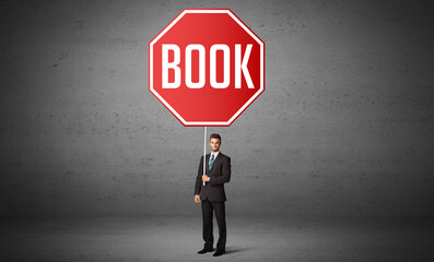 Fototapeta premium Young business person holding road sign with BOOK inscription, new rules concept