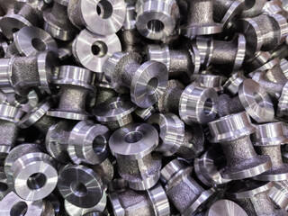 abstract full frame industrial backdrop of forged and turned small steel spool-like parts