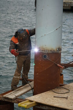 Fototapeta A welder is welding a steel pier pillar at outside