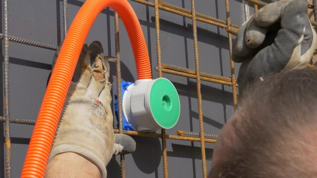 CLOSE UP Unrecognizable contractor strikes his hand against a electricity socket while trying to install it into the outer part of an unfinished wall. Electrician fits plastic frame on unfinished wall