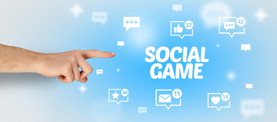 Close-Up of cropped hand pointing at SOCIAL GAME inscription, social networking concept