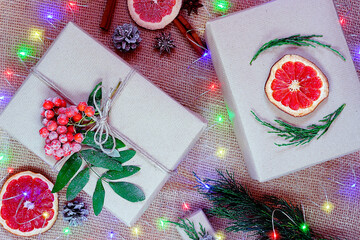 Christmas composition of gift boxes in craft paper on a textured eco background with a garland.The...