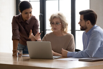 Focused middle aged 60s businesswoman discussing online project presentation with multiracial young...