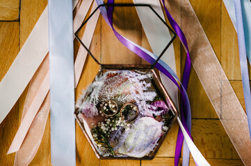 Close-up view of golden wedding rings and beautiful small flowers on wooden background. Top view. Preparation for wedding concept. Engagement.