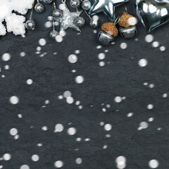 Black Christmas card background with silver decorations and snow on stucco texture