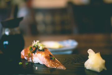 Grilled salmon sushi a bit topping with sauce and black caviar